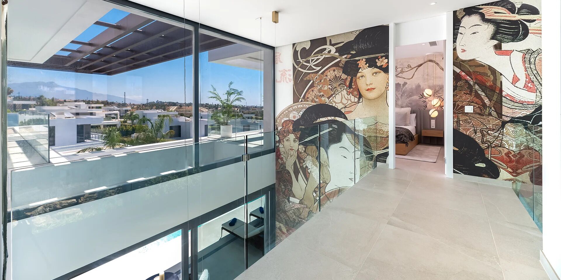A modern interior with a glass balcony overlooking a cityscape, a mural with traditional artwork, and a clean, contemporary design.