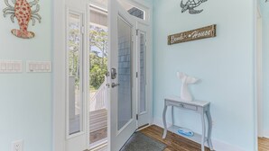 A room with a door, a small table, and wall decorations including a turtle and a sign that reads "Beck House". - Great Location Near Beach, Walk to Restaurants and shops, Fenced in Back Yard (Oak Island)