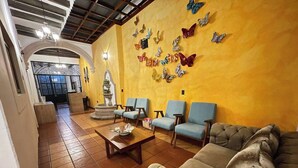 Un vestíbulo con piso de baldosas, una fuente, un sofá y una pared decorada con adornos de mariposas.