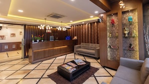 A lobby with a reception desk, a sofa, a coffee table, and decorative items on shelves.