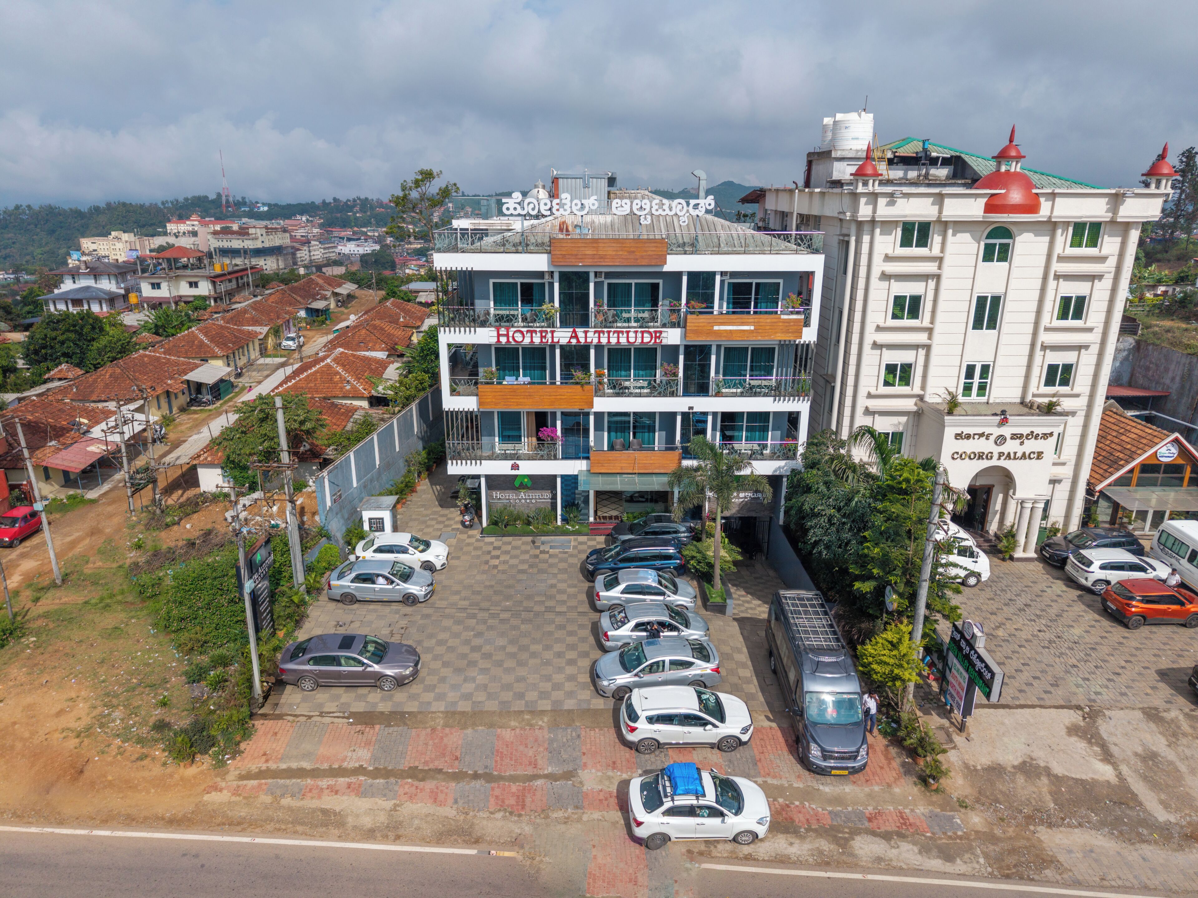 Um hotel com vários andares, área de estacionamento xadrez, varandas e vista para o bairro ao redor.