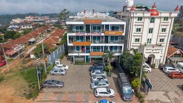 Um hotel com vários andares, área de estacionamento xadrez, varandas e vista para o bairro ao redor.