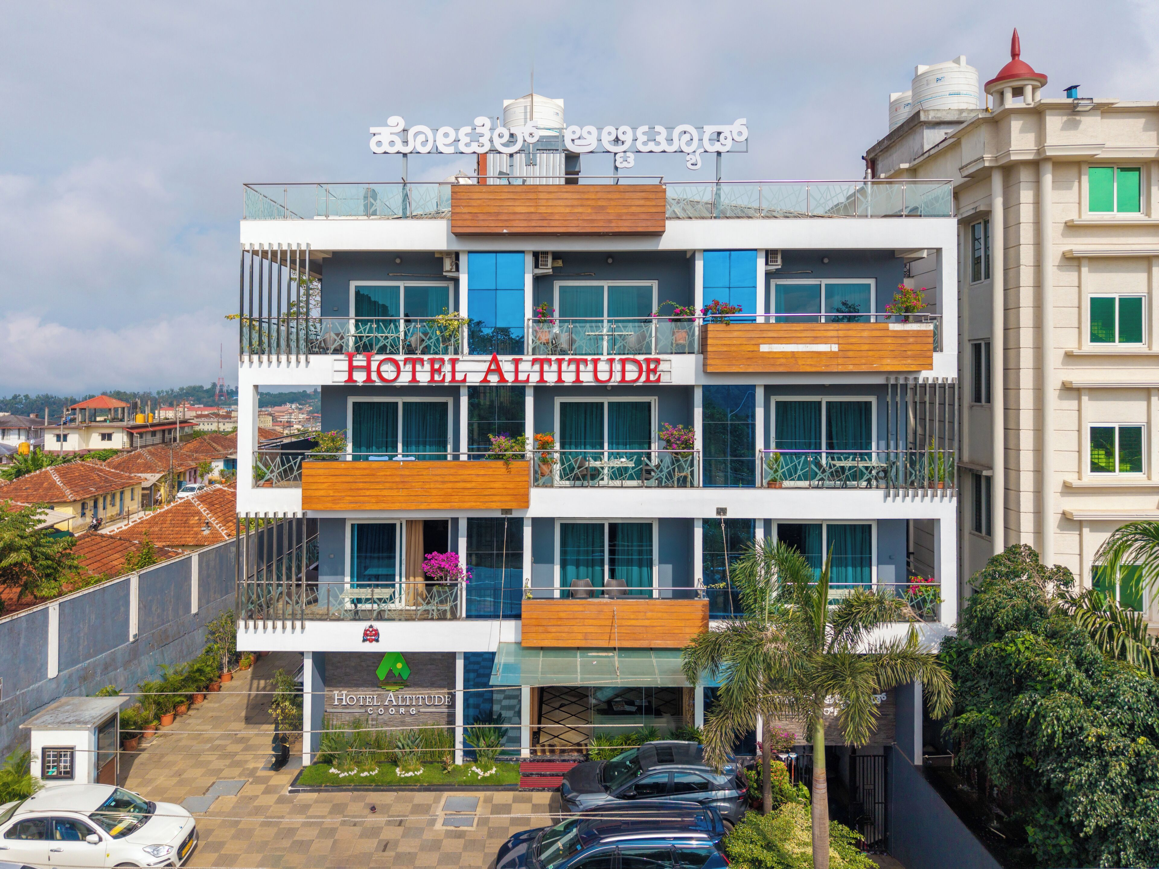 Un hotel de varios pisos con balcones, un cartel que dice 'HOTEL ALTITUDE' y vistas del entorno.