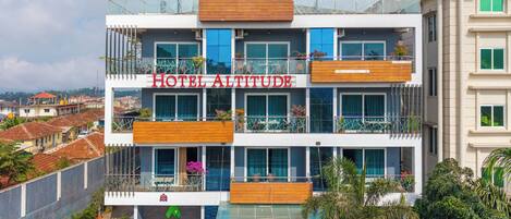 A multi-story hotel with balconies, a sign reading 'HOTEL ALTITUDE,' and a view of the surrounding area.