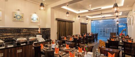 A restaurant with multiple dining tables, chairs, and a buffet area.