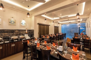 A restaurant with multiple dining tables, chairs, and a buffet area. - Hotel Altitude Coorg (Madikeri)
