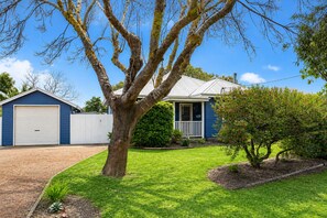 A residential property with a garage, a house with a porch, and a well-maintained lawn. - Relax and Unwind at Otters Retreat (West Busselton)