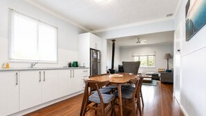 A modern kitchen with white cabinets, a wooden dining table, and a built-in stove. - Relax and Unwind at Otters Retreat (West Busselton)