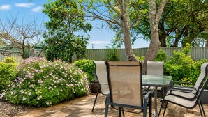 An outdoor patio with a table and chairs, surrounded by greenery and trees. - Relax and Unwind at Otters Retreat (West Busselton)
