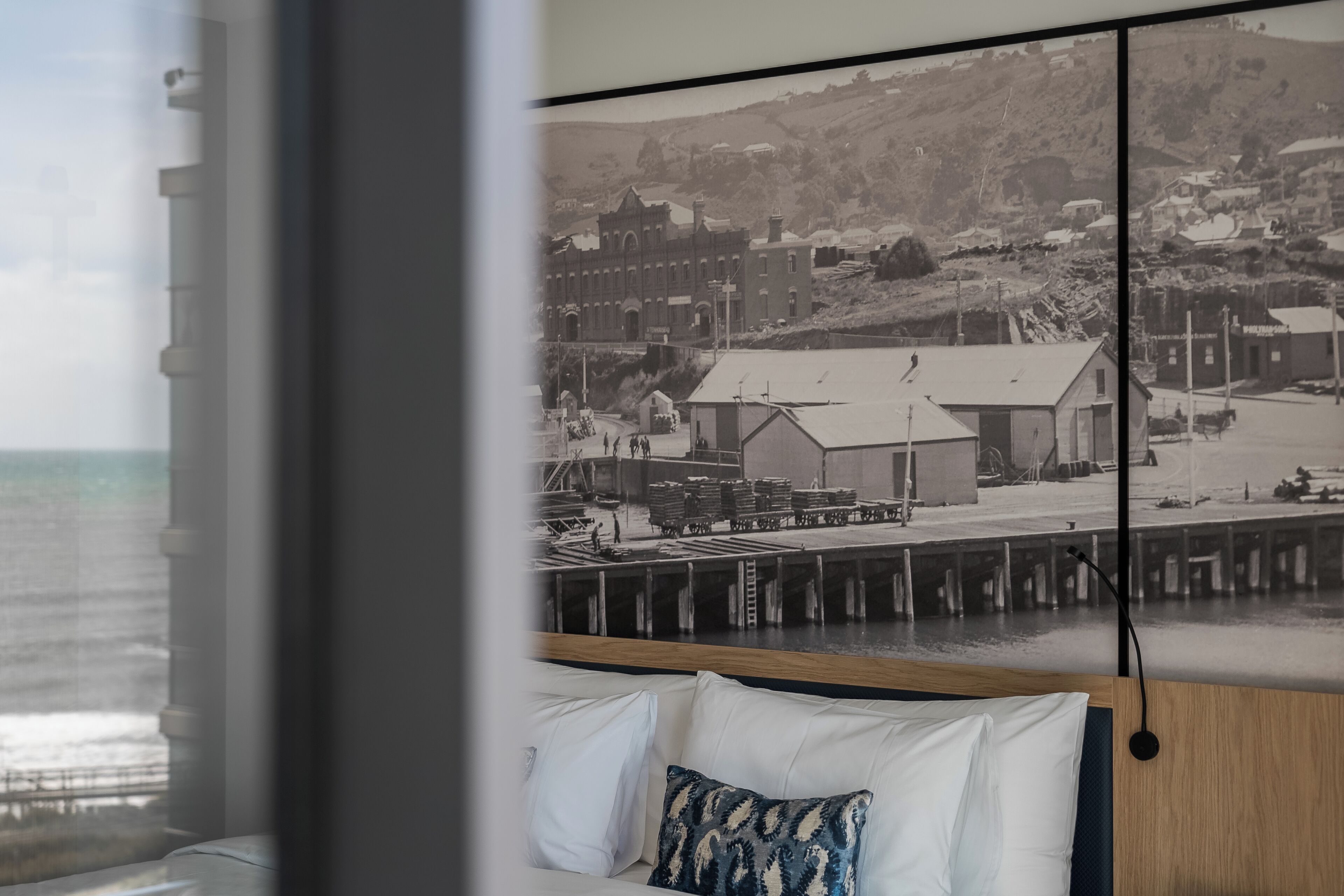 Une chambre avec une grande fenêtre donnant sur une ville côtière.