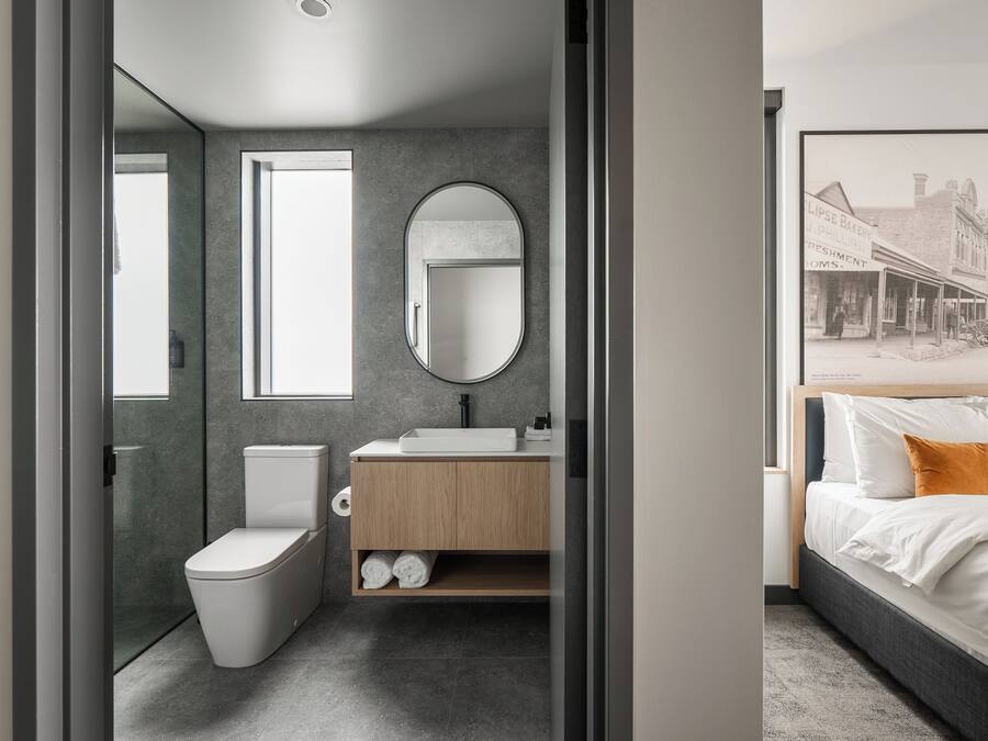 Un baño moderno con inodoro, lavamanos y espejo.