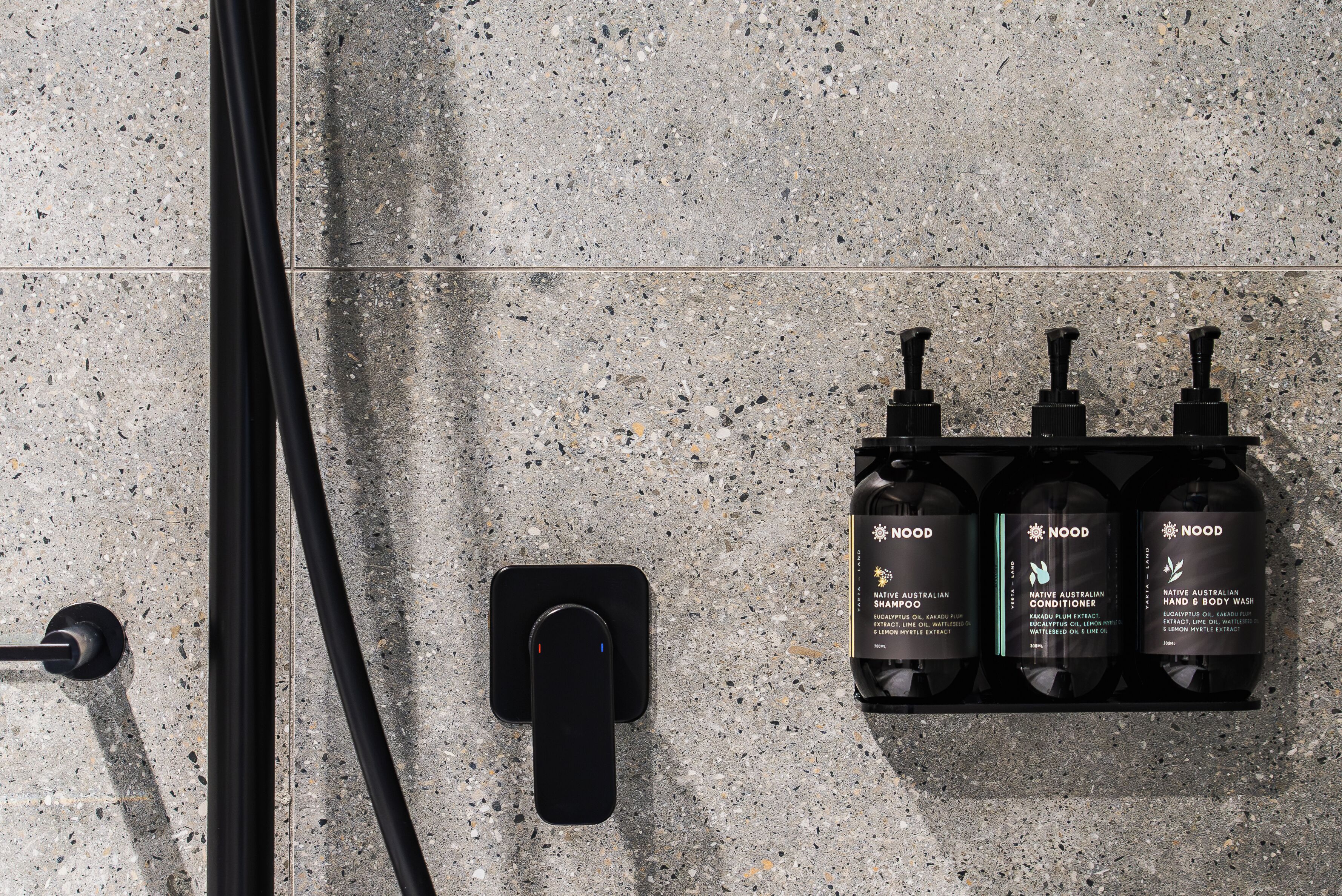 Een wanddispenser met drie flessen Nood douchegel en conditioner.