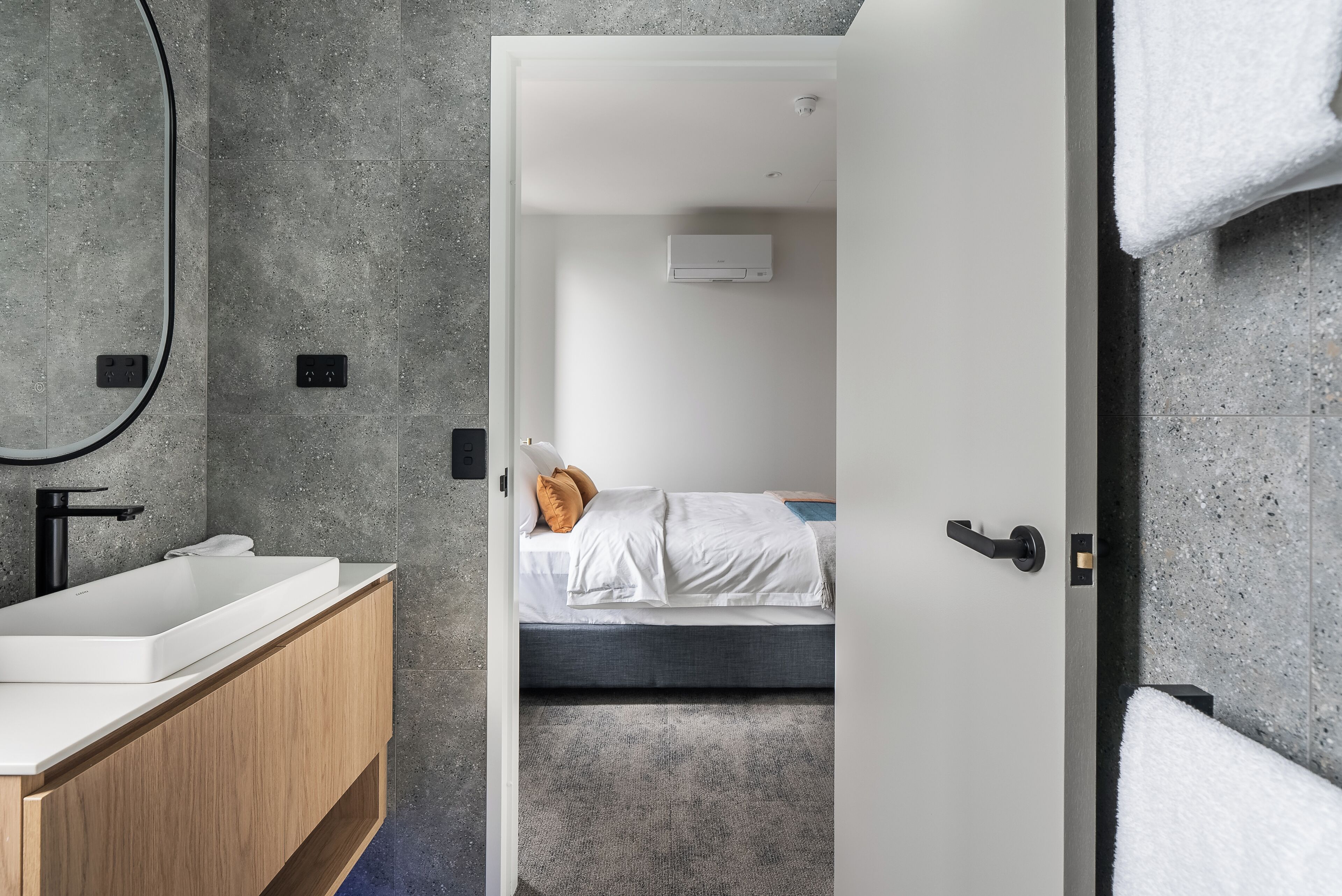 A modern bathroom with a white sink, wooden vanity, and a large mirror.