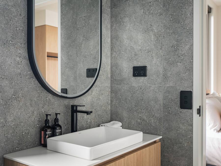 Un baño moderno con un lavabo rectangular, un espejo grande y una toalla sobre el mostrador.