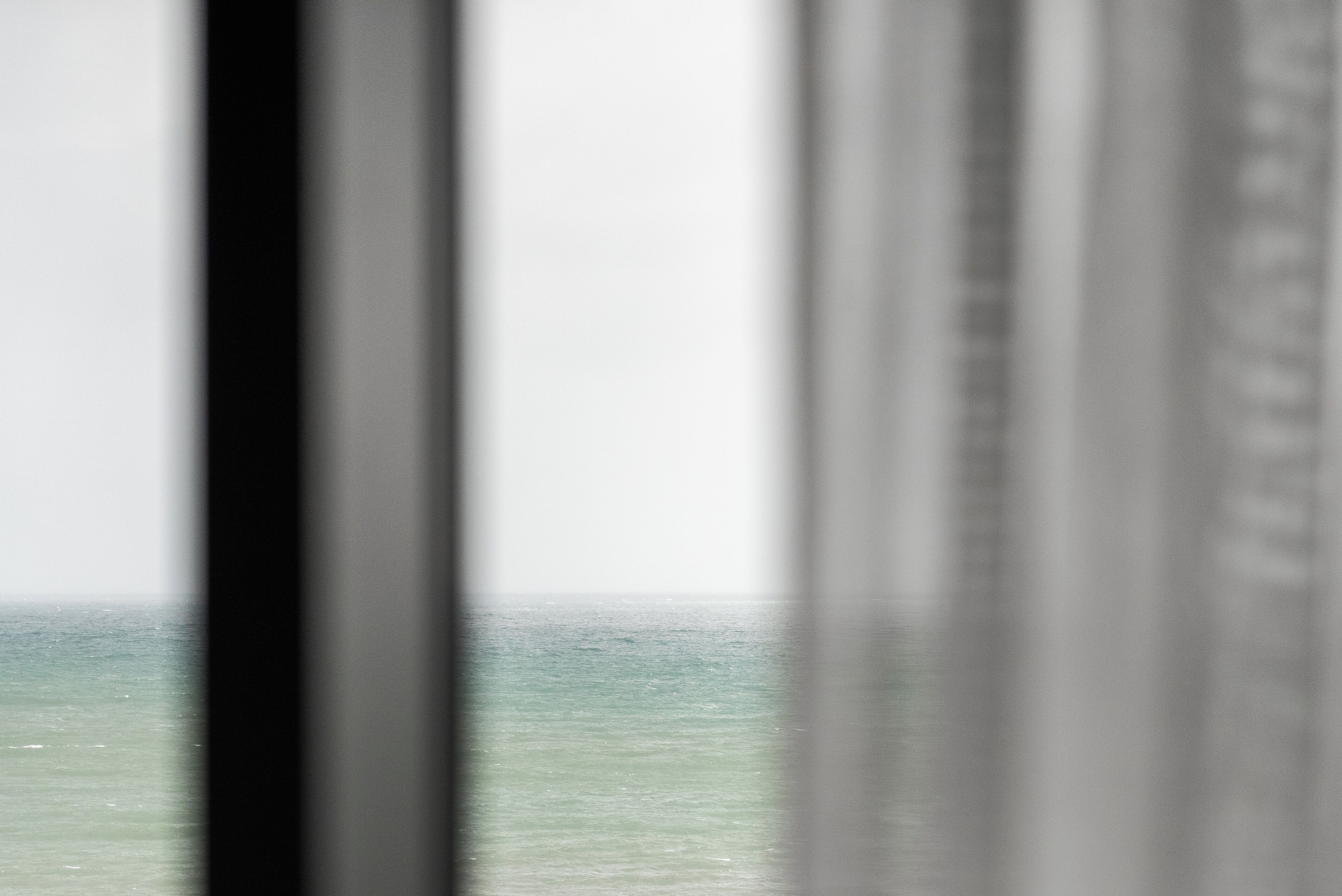 A view through a window with a blurred background, likely an ocean or sea.