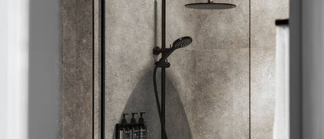 A shower with a handheld showerhead and a wall-mounted faucet, with bottles of shampoo and conditioner on the wall.