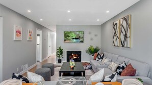 A modern living room with a fireplace, grey sofas, a coffee table, and artwork on the walls.