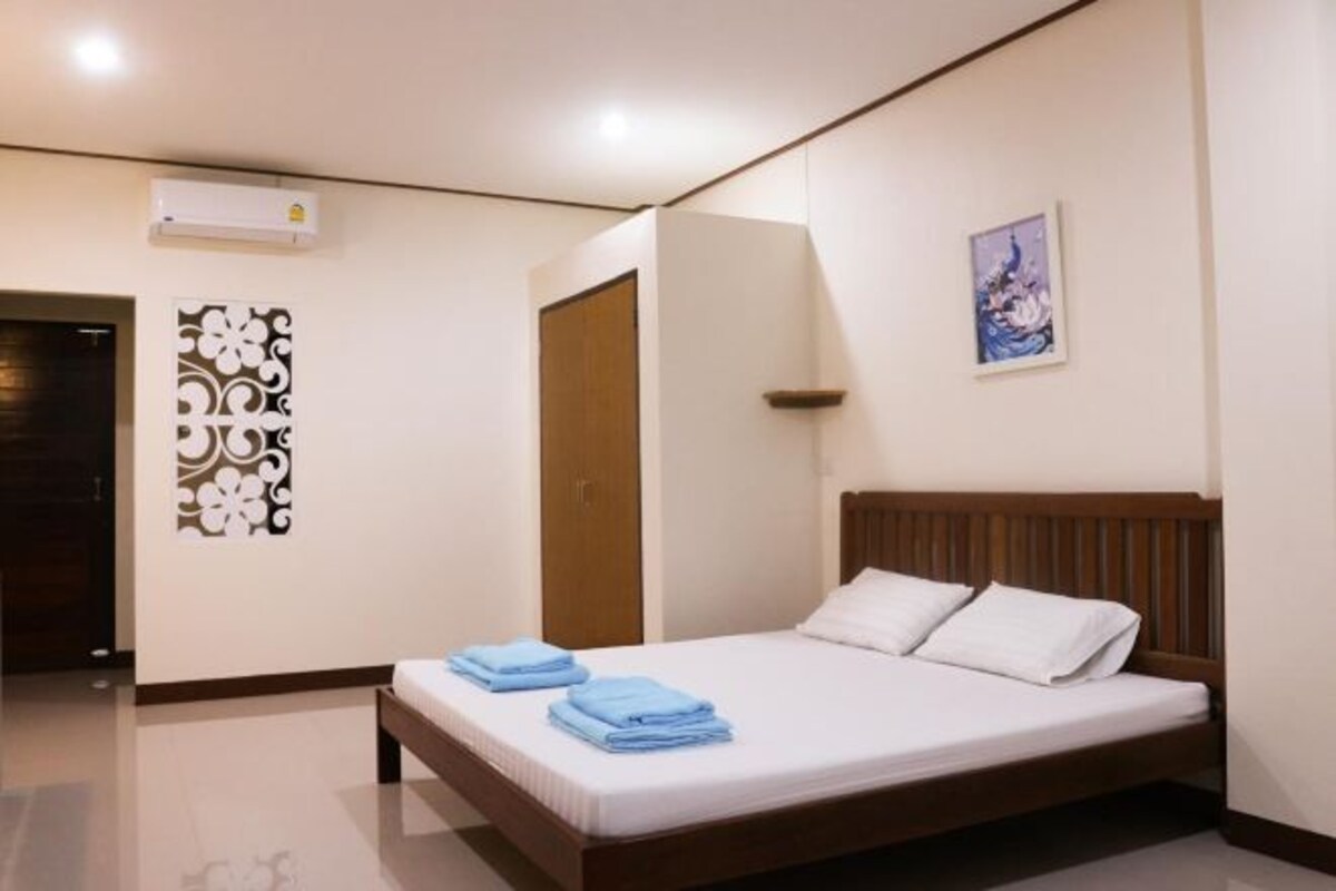 Une chambre d’hôtel moderne avec un lit soigneusement fait, un élément décoratif mural et une œuvre d’art encadrée.
