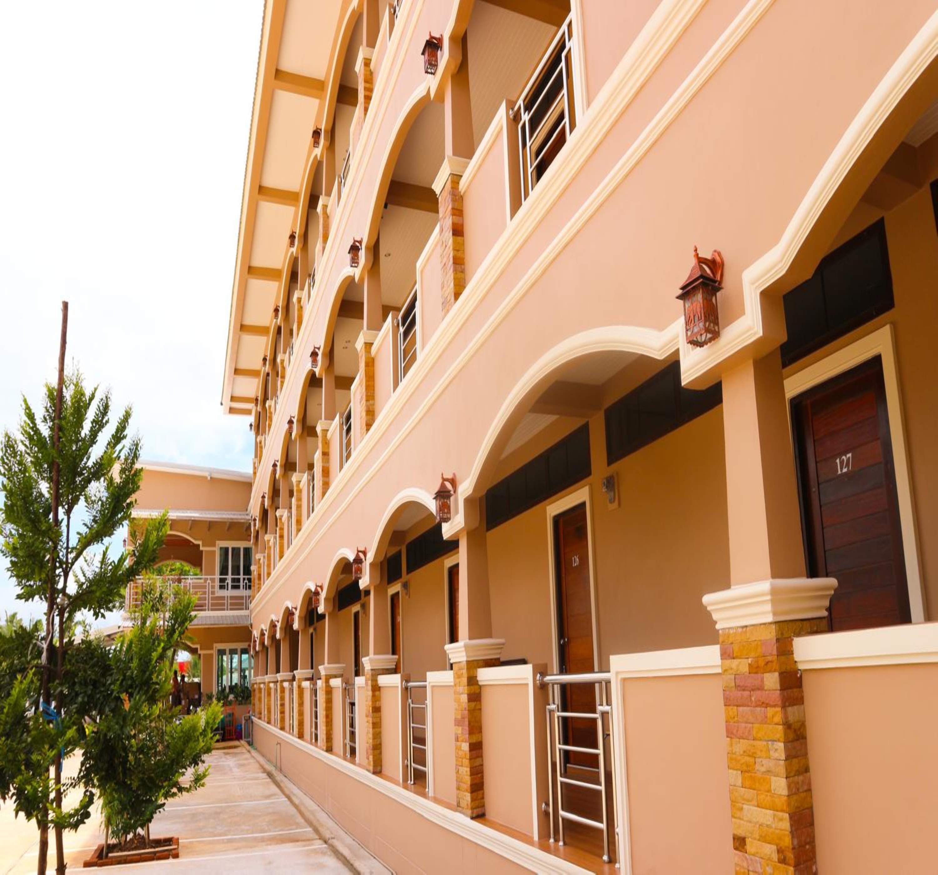Un hotel de varios pisos con un estilo arquitectónico uniforme, que cuenta con balcones con barandillas y varias puertas en la planta baja.