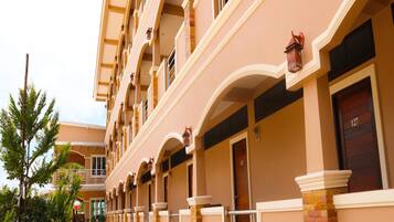 Un hotel de varios pisos con un estilo arquitectónico uniforme, que cuenta con balcones con barandillas y varias puertas en la planta baja.