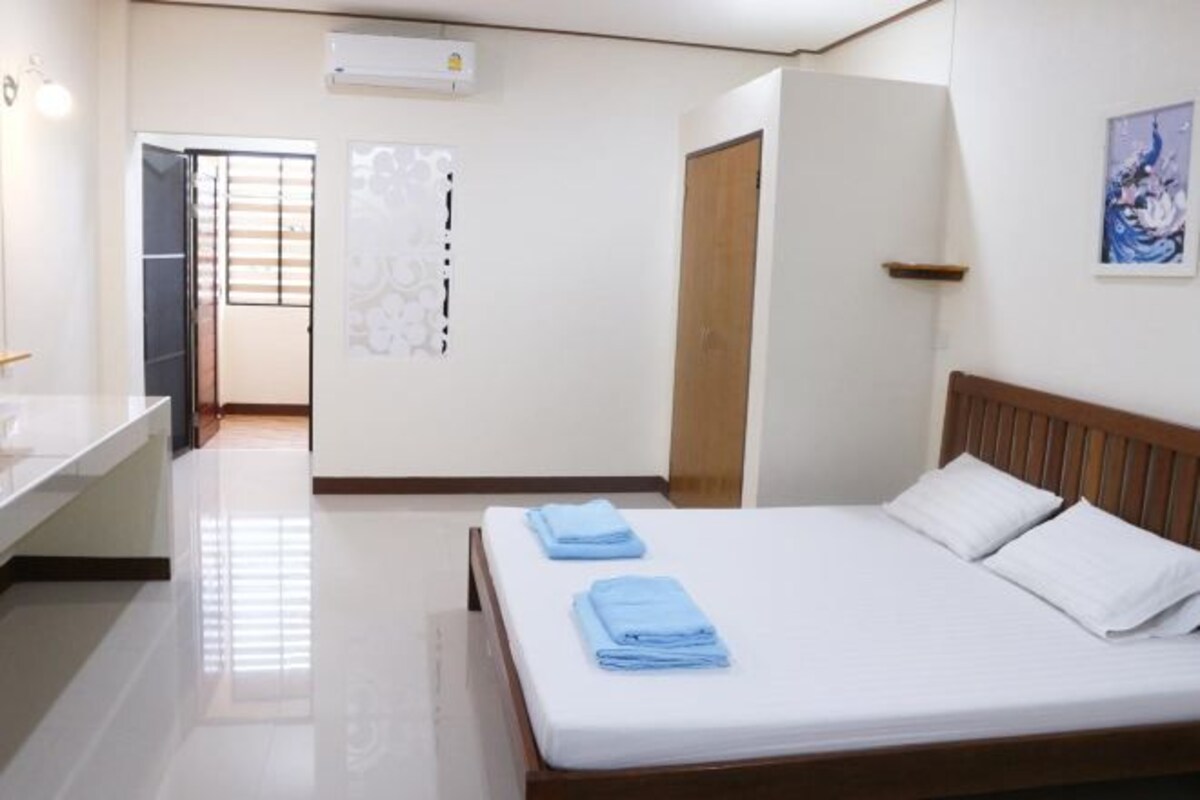 Une chambre d’hôtel comprenant un lit, une table de chevet, un miroir et une porte donnant sur une autre pièce.