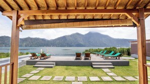 A covered outdoor area with lounge chairs and a view of a lake and mountains. - D Sila’s Tepi Danu Villas Kintamani & Natural hot spring (Kintamani)