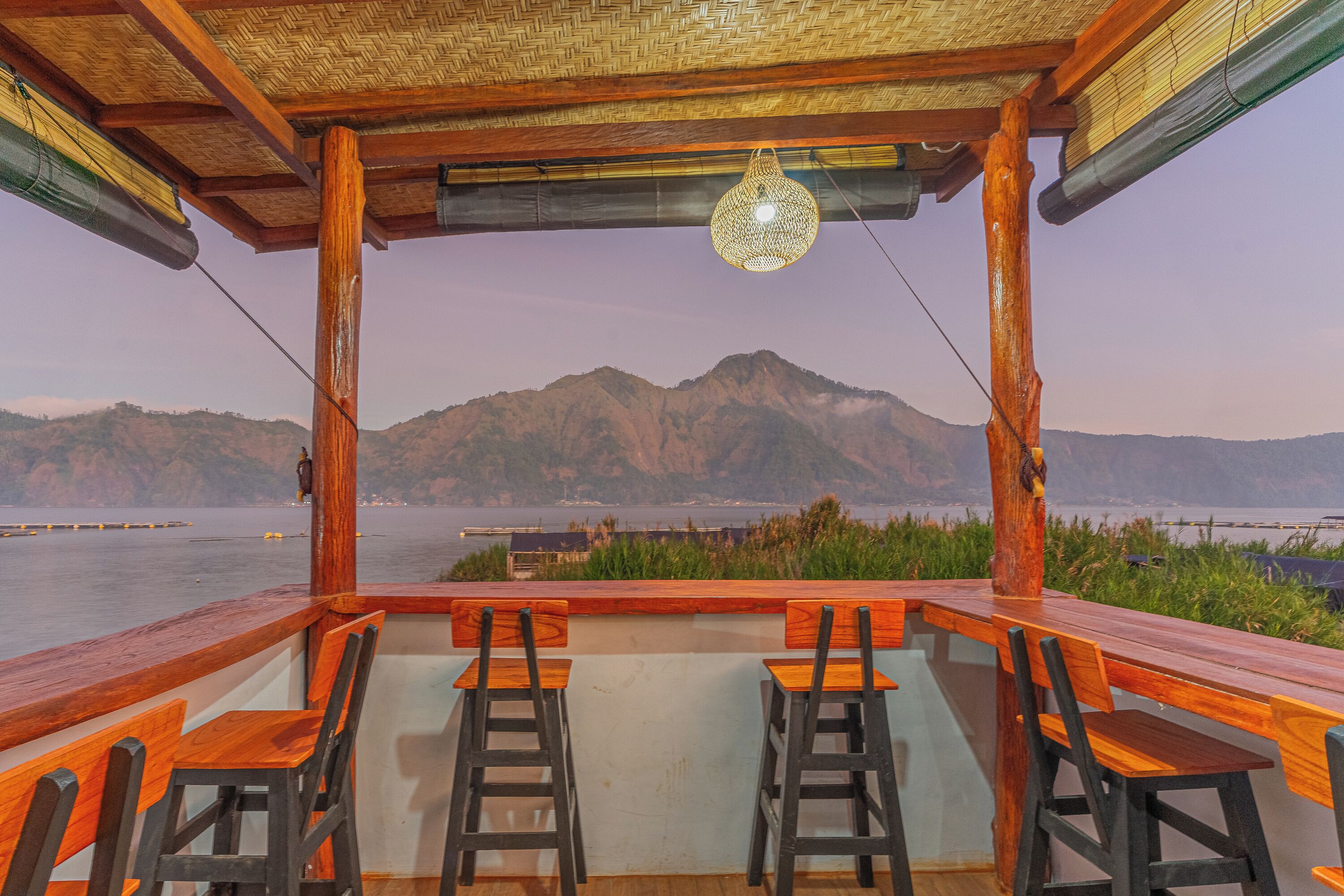 Une terrasse en bois avec des tabourets de bar, donnant sur une étendue d’eau et des montagnes.