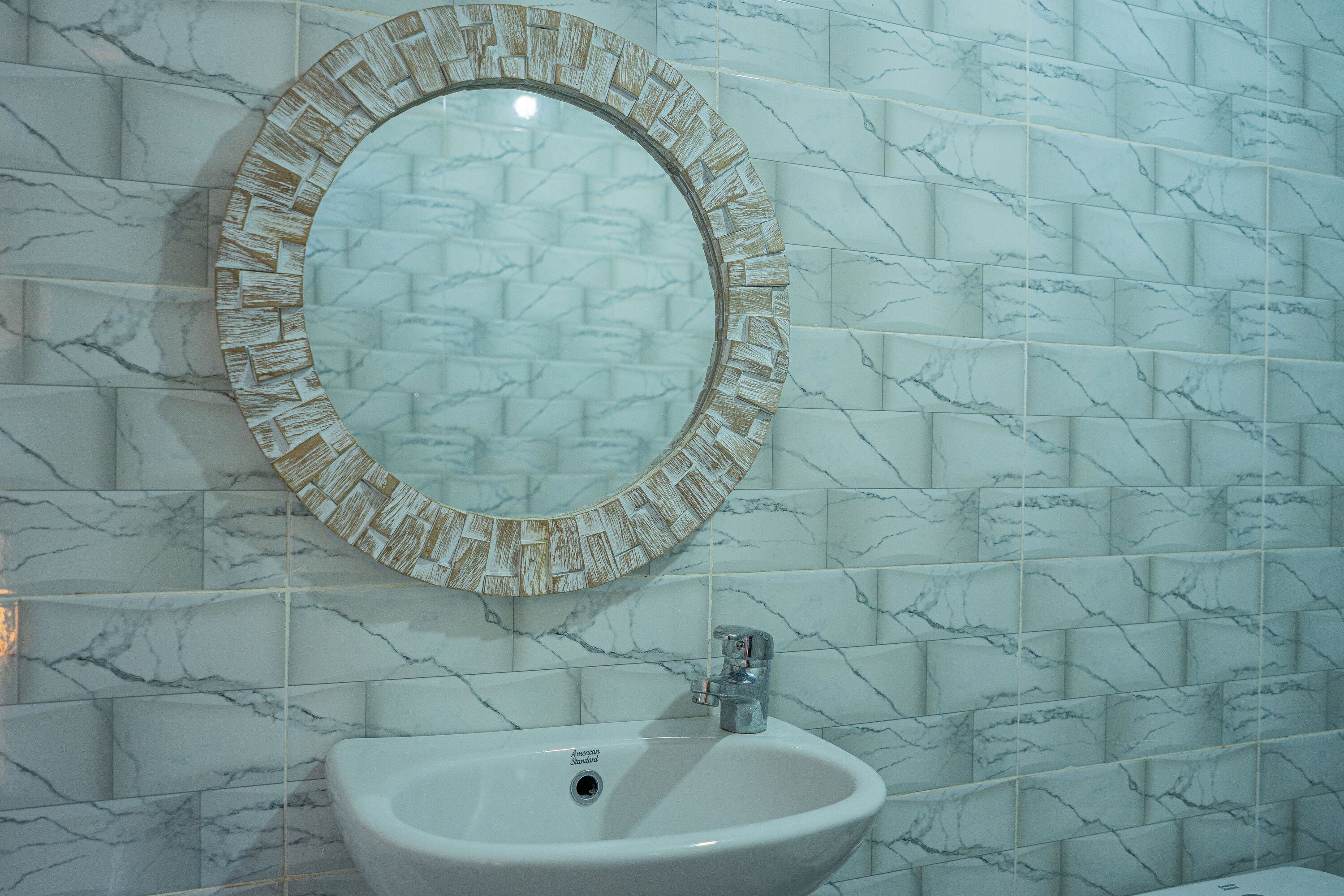Un baño con un espejo redondo y un lavabo.