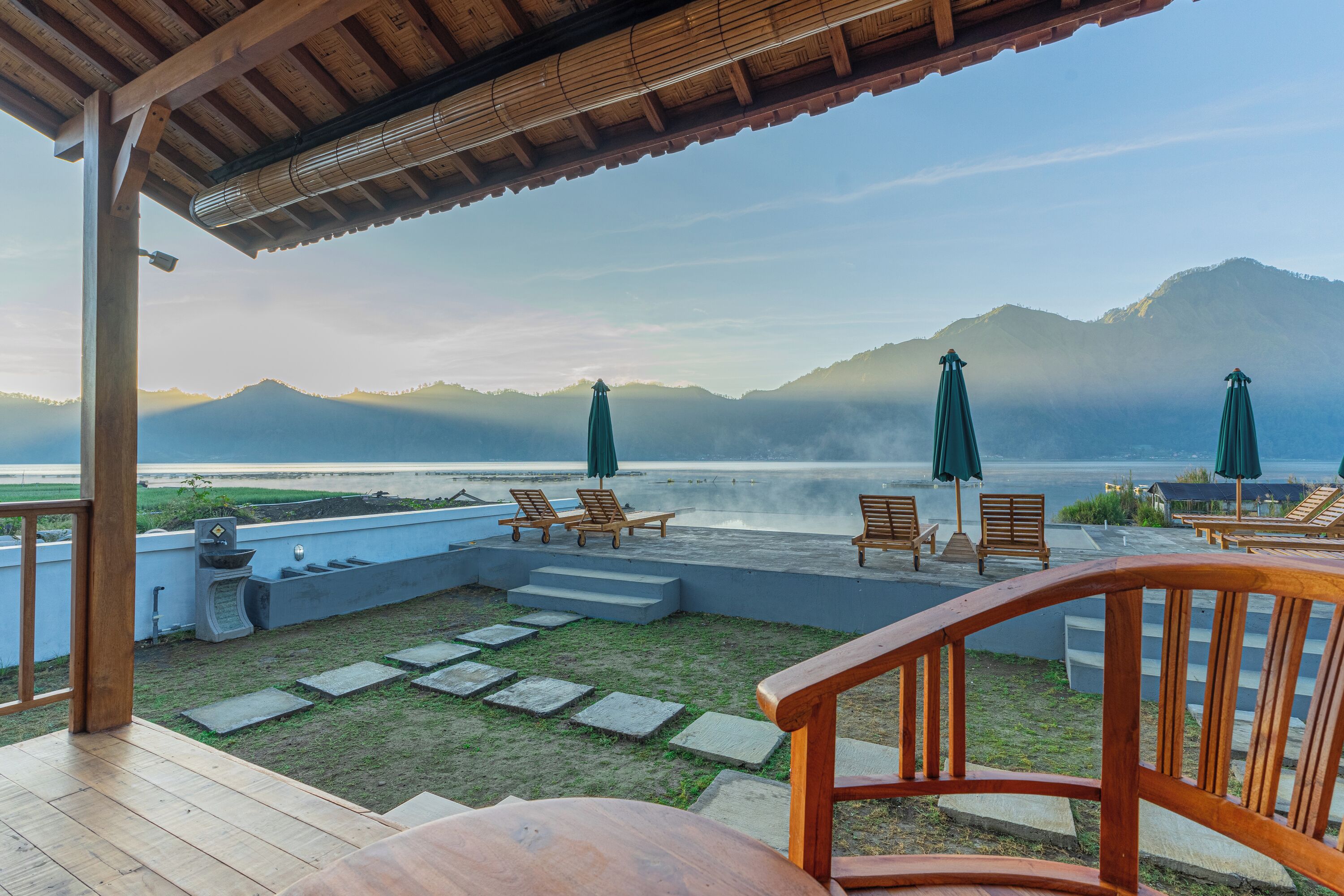 Una terraza de madera con mobiliario exterior y vistas al mar y a las montañas.