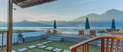 A wooden deck with outdoor seating and a view of the sea and mountains.