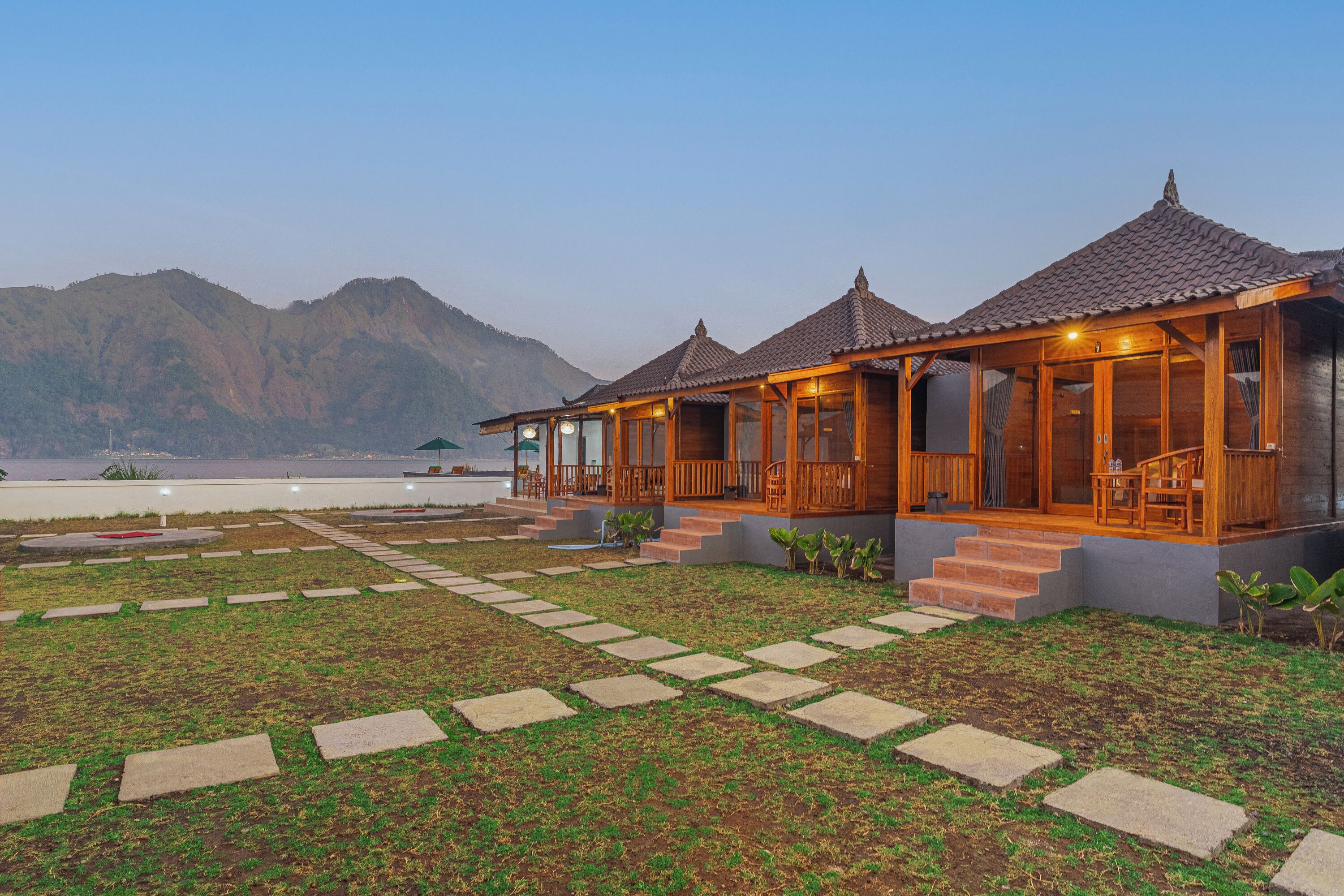 Un resort con cabañas de madera, un sendero de piedra y vistas a las montañas.