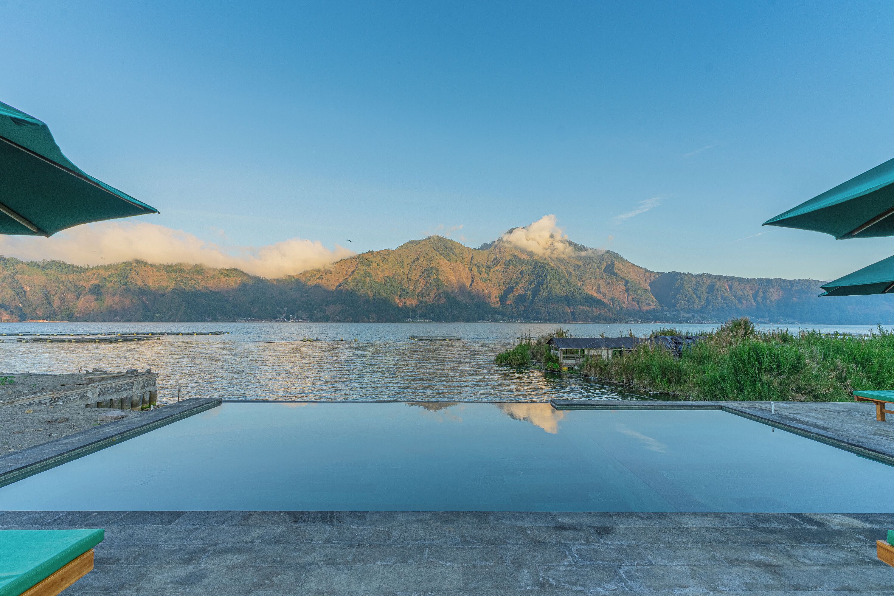 Una piscina infinita con vistas a montañas y una masa de agua.