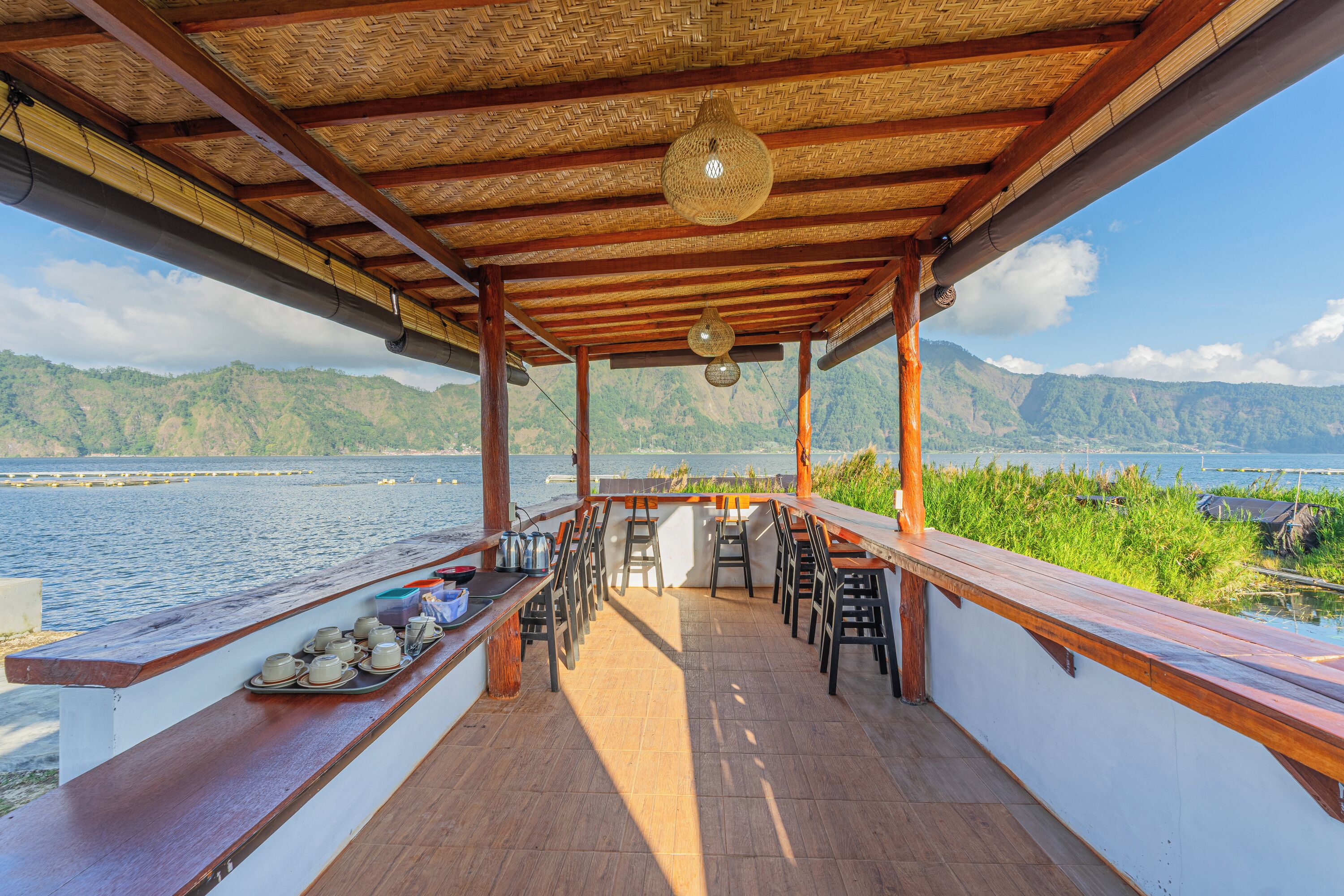 A covered outdoor seating area with a view of a lake and mountains.