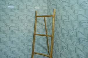 Una escalera de madera apoyada en una pared con baldosas de diseño de mármol.
