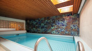 A swimming pool with a tiled floor and walls, a wooden ceiling, and a metal pool ladder. - Hotel Garni Zum Wilden Mann (Künzelsau)