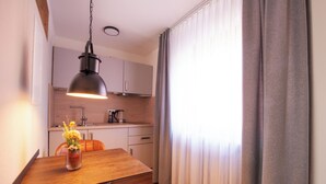 A dining area with a wooden table, chairs, a vase with flowers, a hanging pendant light, and a kitchen in the background. - Hotel Garni Zum Wilden Mann (Künzelsau)