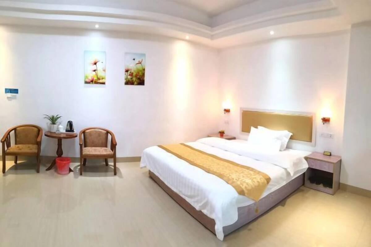 A hotel room with a large bed, two chairs, a small table, and wall art.