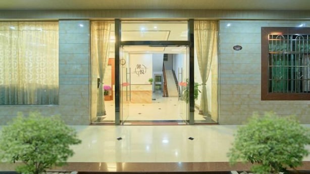 A hotel entrance with a glass door, a staircase leading inside, and potted plants on either side. - Mount Danxia Xin Yue Inn (Renhua)
