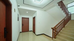 A hallway with a wooden door, a staircase with a wooden railing, and a ceiling light fixture. - Mount Danxia Xin Yue Inn (Renhua)