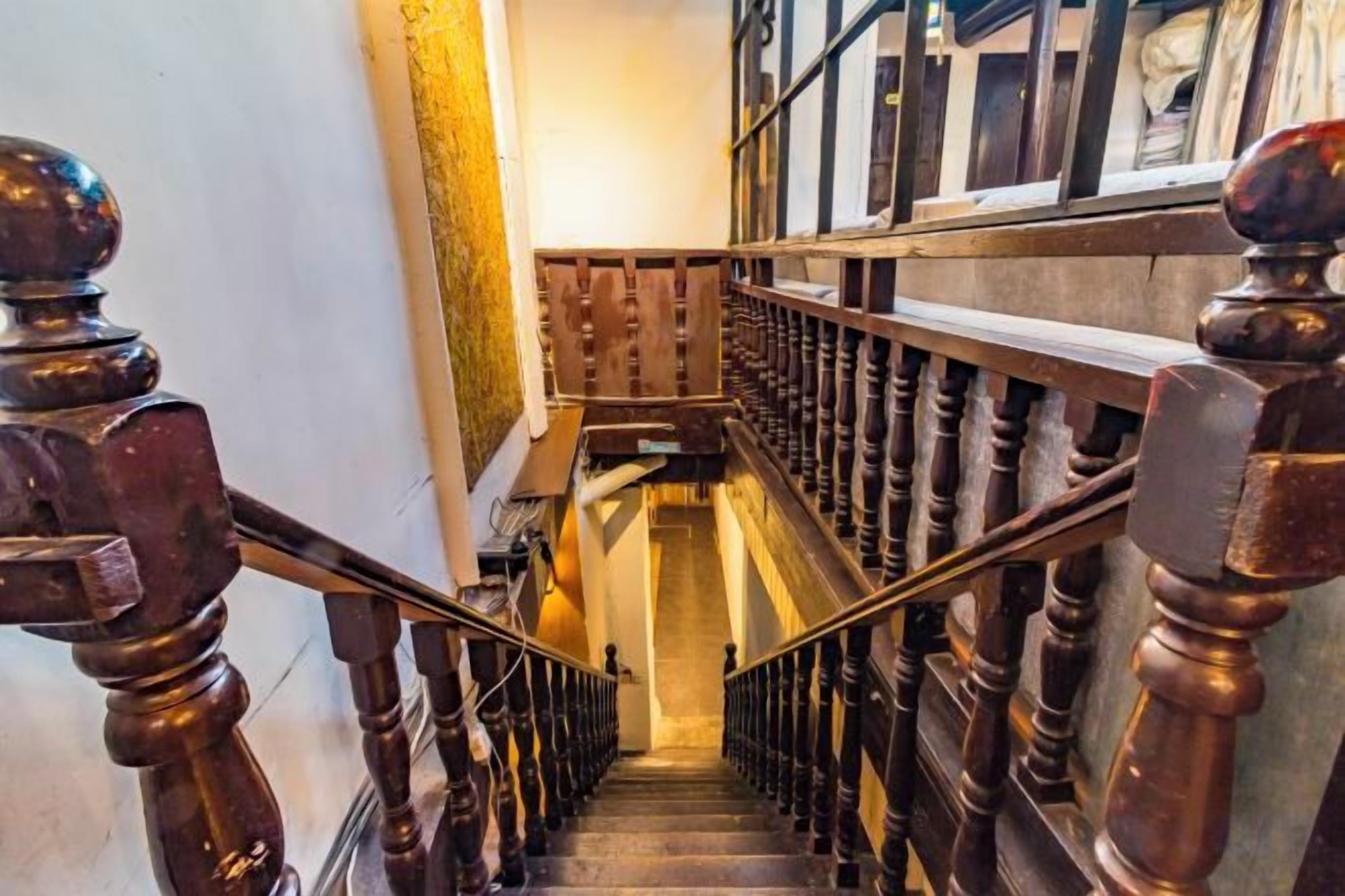 A wooden staircase with a handrail and balusters, leading to an upper floor.