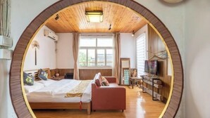 Una habitación circular con cama, sofá, televisión y ventana.