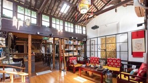 Una habitación en estilo tradicional japonés con suelo de tatami, muebles de madera y una estantería.