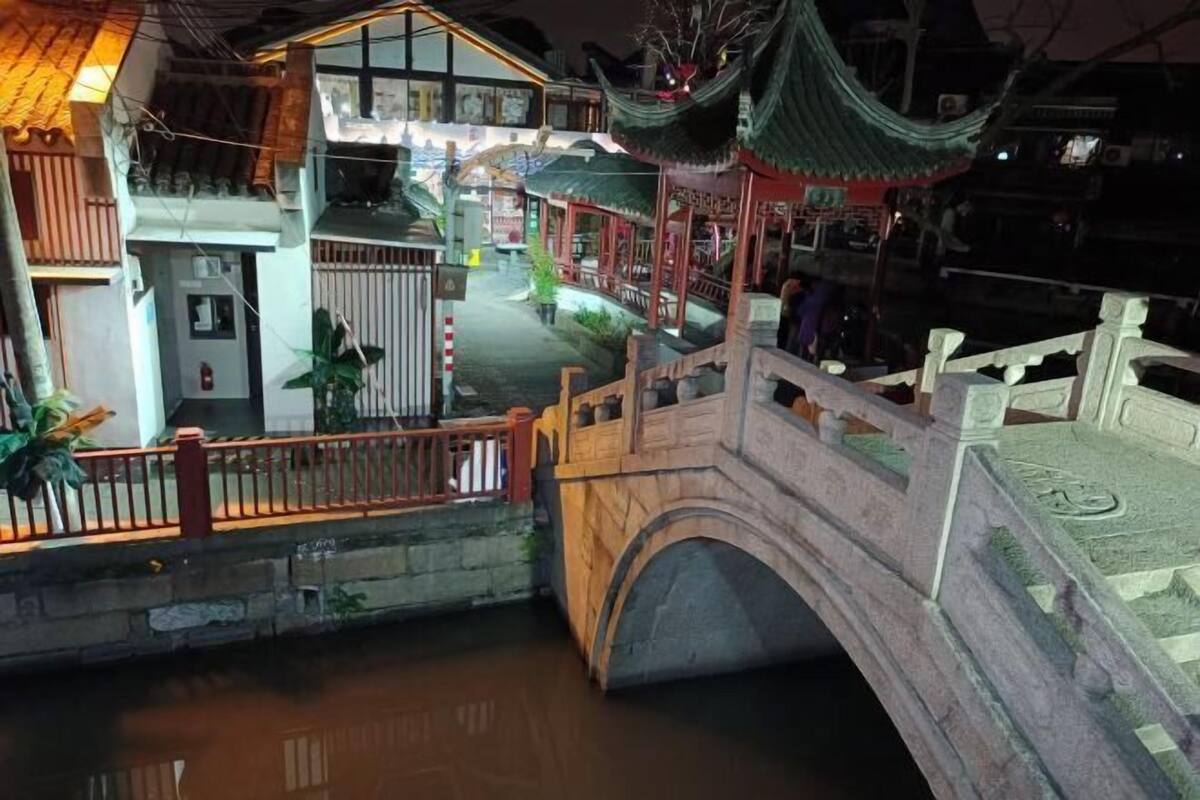A traditional Chinese-style building with a wooden bridge over a canal.