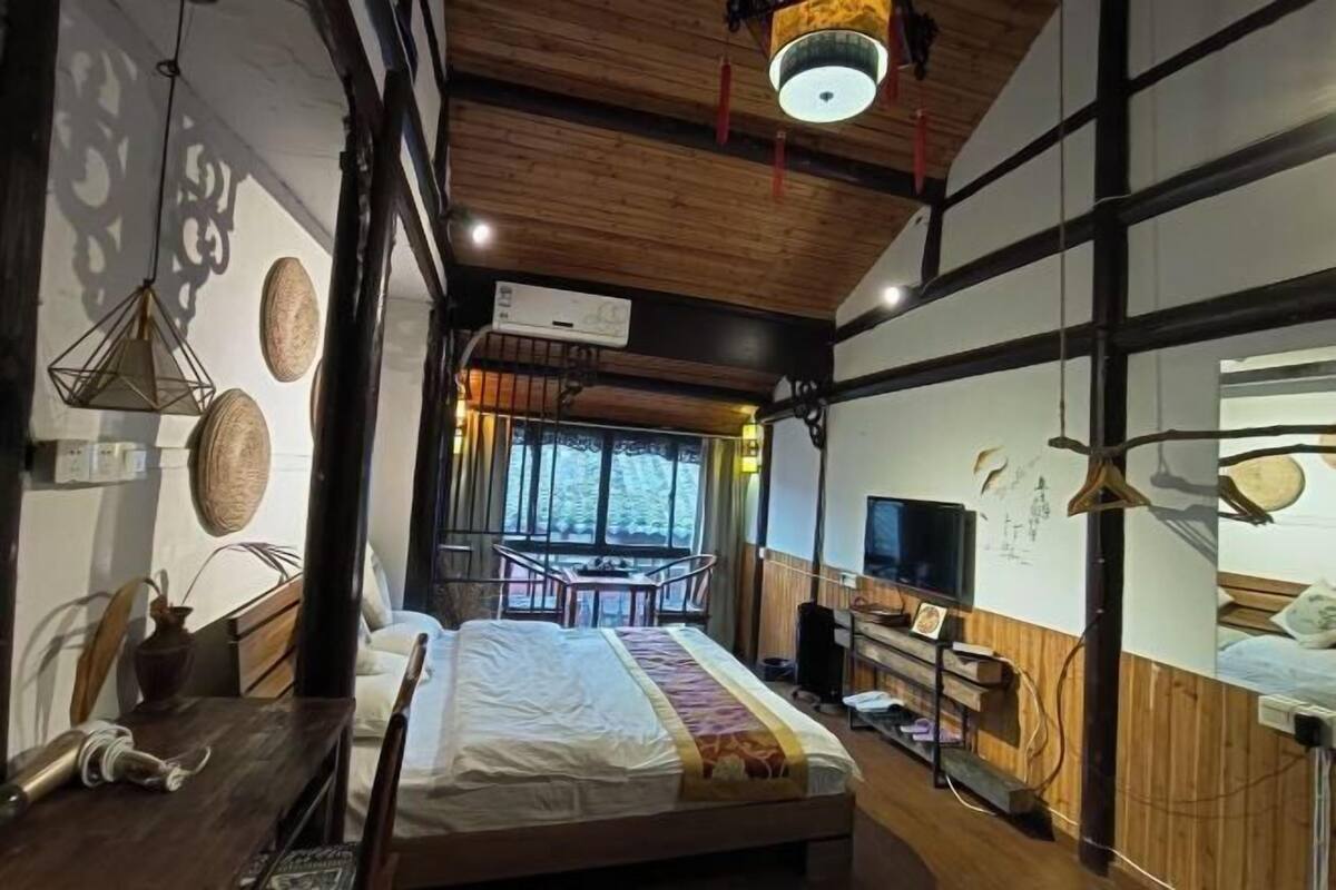 A hotel room with a bed, wooden ceiling, a TV, and a window with a view.