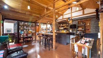 Una habitación amplia con techo de madera, una zona de bar y un área de estar con chimenea.