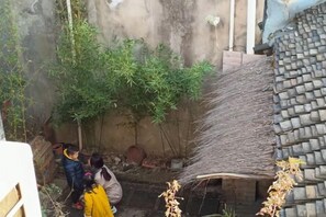 Un patio con techo de tejas tradicionales, una pequeña estructura de ladrillo y un árbol.