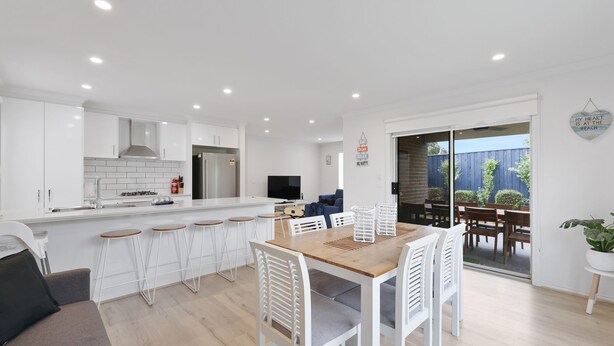 A modern kitchen with white cabinets, a built-in oven, and a stainless steel refrigerator. - Life's a Beach Shack (Cowes)