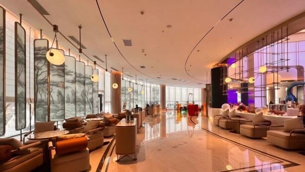 A spacious lobby with modern seating, large windows, and a curved ceiling. - Vest Holiday Hotel (Urumqi)