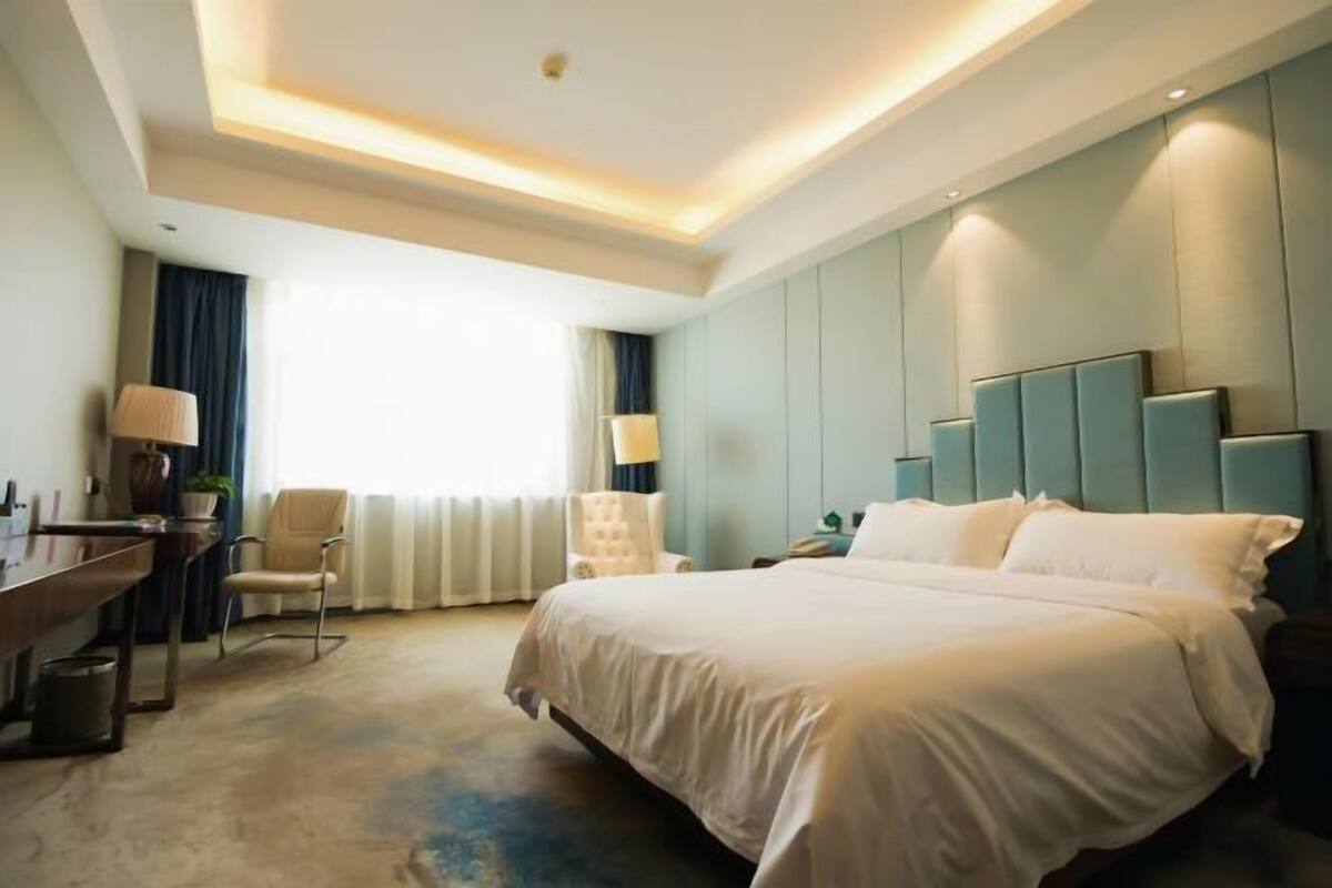 Ein Hotelzimmer mit einem großen Bett, einem Schreibtisch und einem Stuhl.