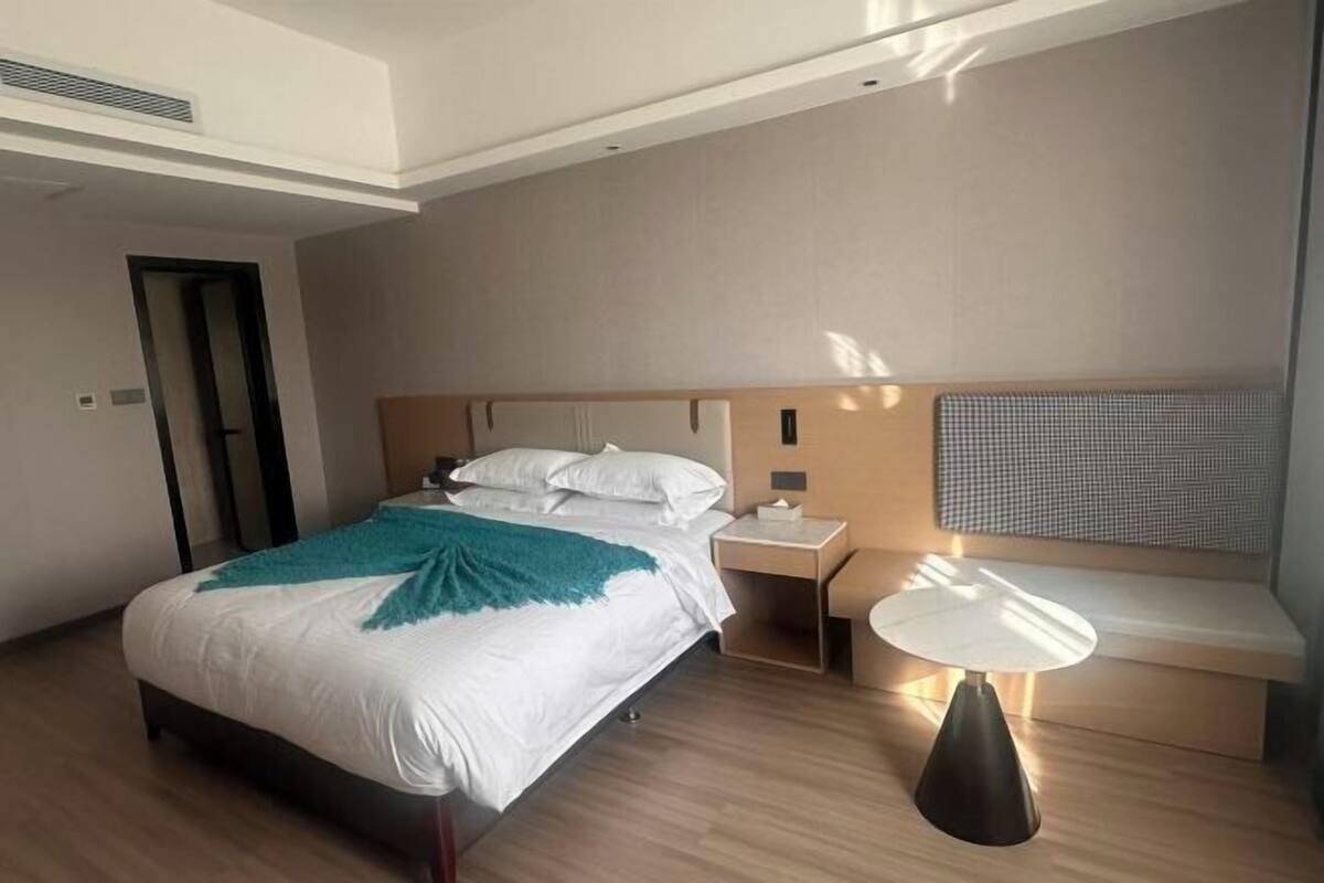 Ein modernes Hotelzimmer mit Bett, Nachttisch, Lampe und integriertem Sitzplatz.